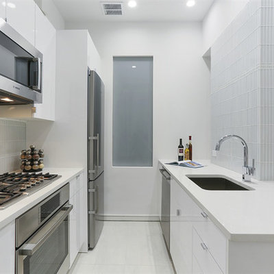 Eat-in kitchen - small modern galley white floor and porcelain tile eat-in kitchen idea in New York with an undermount sink, flat-panel cabinets, white cabinets, glass tile backsplash, stainless steel appliances, no island, quartz countertops, white backsplash and white countertops