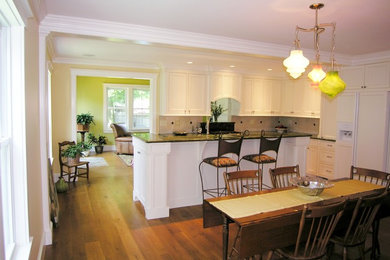 This is an example of a small classic l-shaped kitchen/diner in Boston with a submerged sink, recessed-panel cabinets, granite worktops, white splashback, stone tiled splashback, stainless steel appliances, white cabinets, medium hardwood flooring and an island.