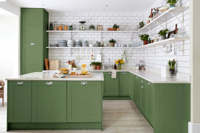 Modelo de cocina de estilo de casa de campo con armarios abiertos, puertas de armario verdes, una isla y suelo gris