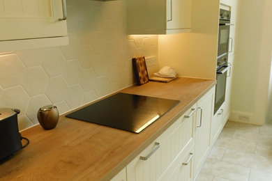 Exempel på ett mellanstort klassiskt kök, med släta luckor, laminatbänkskiva, stänkskydd i porslinskakel, svarta vitvaror och vinylgolv