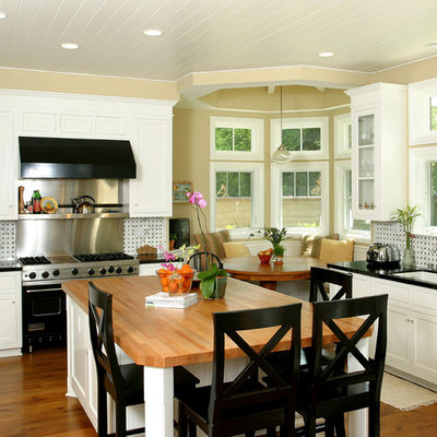 Example of a classic kitchen design in Orange County with wood countertops, shaker cabinets, white cabinets and black appliances