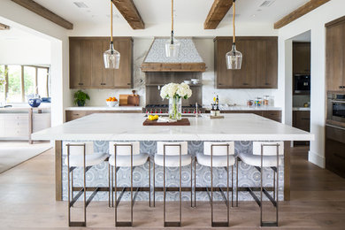 Inspiration for a large mediterranean l-shaped medium tone wood floor and brown floor open concept kitchen remodel in Orange County with flat-panel cabinets, medium tone wood cabinets, white backsplash, stainless steel appliances, an island and white countertops