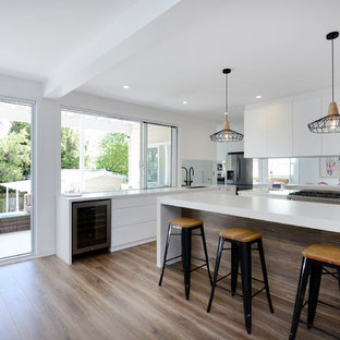 Design ideas for a large contemporary l-shaped eat-in kitchen in Sydney with an undermount sink, flat-panel cabinets, white cabinets, mirror splashback, stainless steel appliances, medium hardwood floors, with island and brown floor.