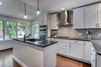 Inspiration for a mid-sized transitional l-shaped dark wood floor eat-in kitchen remodel in Boston with an undermount sink, shaker cabinets, white cabinets, soapstone countertops, gray backsplash, stone tile backsplash, stainless steel appliances and an island