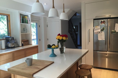 Example of a large trendy light wood floor and brown floor kitchen design in Boston with flat-panel cabinets, light wood cabinets, stainless steel appliances and an island