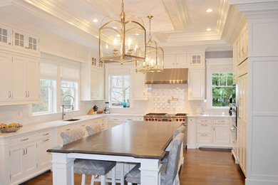 Inspiration for a large contemporary u-shaped medium tone wood floor enclosed kitchen remodel in Boston with an undermount sink, shaker cabinets, white cabinets, soapstone countertops, white backsplash, subway tile backsplash, paneled appliances and an island