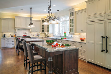 Large transitional l-shaped dark wood floor and brown floor open concept kitchen photo in Boston with two islands, a farmhouse sink, beaded inset cabinets, white cabinets, granite countertops, gray backsplash, subway tile backsplash and paneled appliances