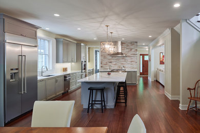 Inspiration for a mid-sized craftsman l-shaped dark wood floor and brown floor eat-in kitchen remodel in Philadelphia with recessed-panel cabinets, blue cabinets, marble countertops, brown backsplash, porcelain backsplash, stainless steel appliances, an island and an undermount sink