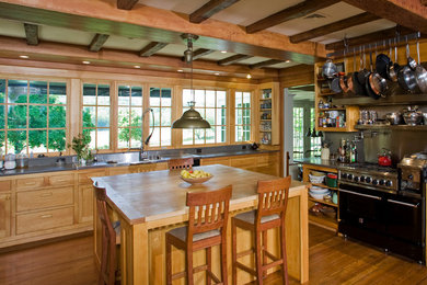 Example of a mountain style kitchen design in Philadelphia with wood countertops, medium tone wood cabinets and black appliances