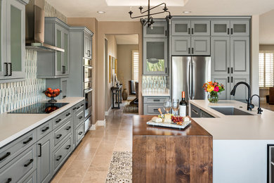 Design ideas for a medium sized traditional kitchen in Phoenix with a single-bowl sink, grey cabinets, engineered stone countertops, glass tiled splashback, stainless steel appliances, limestone flooring, an island, beige floors, white worktops, raised-panel cabinets and multi-coloured splashback.