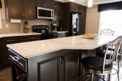 Example of a mid-sized transitional galley dark wood floor and brown floor enclosed kitchen design in Cincinnati with a double-bowl sink, recessed-panel cabinets, dark wood cabinets, quartz countertops, white backsplash, subway tile backsplash, black appliances and an island