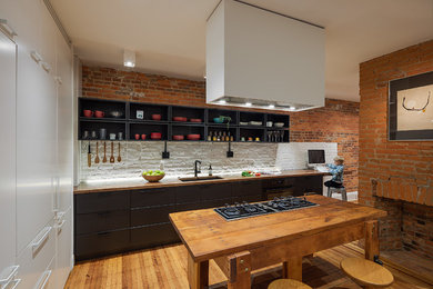 Inspiration for a mid-sized modern medium tone wood floor and brown floor eat-in kitchen remodel in Philadelphia with an undermount sink, flat-panel cabinets, black cabinets, wood countertops, white backsplash, brick backsplash, black appliances, an island and brown countertops