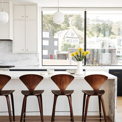 Example of a large mid-century modern light wood floor and beige floor open concept kitchen design in San Francisco with a farmhouse sink, flat-panel cabinets, white cabinets, white backsplash, stone slab backsplash, an island, white countertops and marble countertops