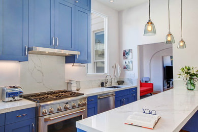 Photo of a small contemporary u-shaped kitchen in San Francisco with a submerged sink, shaker cabinets, blue cabinets, engineered stone countertops, white splashback, marble splashback, stainless steel appliances, light hardwood flooring, a breakfast bar and white worktops.