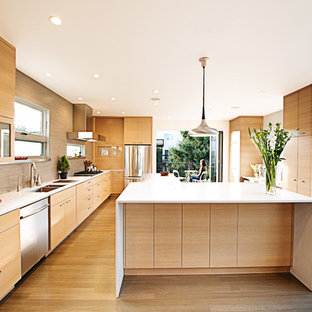 Ispirazione per una cucina moderna chiusa con elettrodomestici in acciaio inossidabile, ante lisce, ante in legno chiaro, paraspruzzi beige e paraspruzzi con piastrelle a listelli