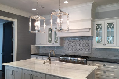 Kitchen - contemporary l-shaped kitchen idea in Houston with a farmhouse sink, beaded inset cabinets, white cabinets, marble countertops, marble backsplash, stainless steel appliances and an island