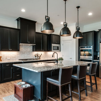 Inspiration for a mid-sized transitional medium tone wood floor and brown floor eat-in kitchen remodel in Nashville with an undermount sink, shaker cabinets, black cabinets, granite countertops, gray backsplash, limestone backsplash, stainless steel appliances, an island and multicolored countertops