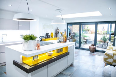 Design ideas for a large eclectic l-shaped kitchen/diner in Manchester with an integrated sink, white cabinets, engineered stone countertops, white splashback, stainless steel appliances, porcelain flooring, an island, grey floors, white worktops and flat-panel cabinets.