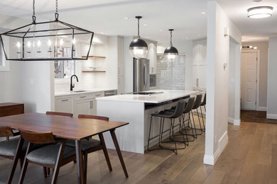 Mid-sized arts and crafts u-shaped medium tone wood floor eat-in kitchen photo in Vancouver with an undermount sink, shaker cabinets, gray cabinets, quartz countertops, white backsplash, porcelain backsplash, stainless steel appliances, an island and white countertops