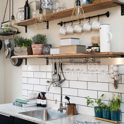 Kitchen - small rustic single-wall kitchen idea in Gothenburg with a drop-in sink, flat-panel cabinets, black cabinets, granite countertops and no island