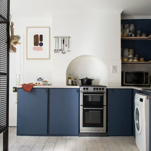 Medium sized scandinavian l-shaped enclosed kitchen in Kent with flat-panel cabinets, blue cabinets, laminate countertops, white splashback, cement tile splashback, stainless steel appliances, light hardwood flooring, no island, white floors and beige worktops.