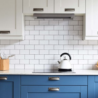 Photo of a mid-sized contemporary u-shaped eat-in kitchen in Other with a farmhouse sink, shaker cabinets, blue cabinets, recycled glass benchtops, white splashback, ceramic splashback, linoleum floors, a peninsula and grey floor.