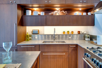 This is an example of a contemporary l-shaped kitchen/diner in New York with a submerged sink, flat-panel cabinets, medium wood cabinets, engineered stone countertops, metallic splashback, metal splashback and integrated appliances.