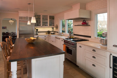 シアトルにある高級なトラディショナルスタイルのおしゃれなキッチン (エプロンフロントシンク、落し込みパネル扉のキャビネット、白いキャビネット、木材カウンター、白いキッチンパネル、サブウェイタイルのキッチンパネル、パネルと同色の調理設備) の写真