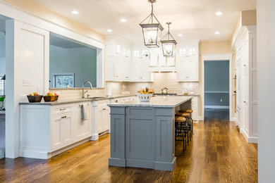 Inspiration for a mid-sized timeless u-shaped dark wood floor enclosed kitchen remodel in Boston with an undermount sink, shaker cabinets, stainless steel appliances, an island, white cabinets, granite countertops, beige backsplash and porcelain backsplash