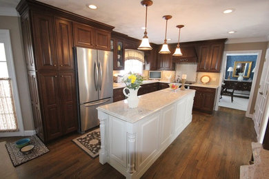 Example of a large classic l-shaped dark wood floor enclosed kitchen design in Providence with raised-panel cabinets, dark wood cabinets, granite countertops, beige backsplash, an island, ceramic backsplash, stainless steel appliances and an undermount sink