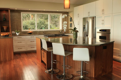 Example of a large trendy u-shaped medium tone wood floor open concept kitchen design in Seattle with an undermount sink, shaker cabinets, white cabinets, granite countertops, green backsplash, glass tile backsplash, stainless steel appliances and an island