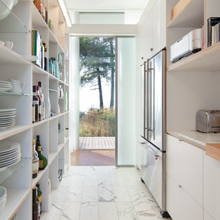 This is an example of a modern galley separate kitchen in Seattle with stainless steel appliances, marble floors, flat-panel cabinets, white cabinets, wood benchtops and no island.