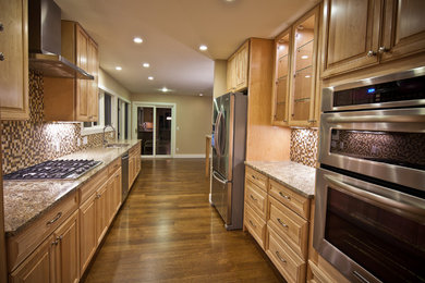 Enclosed kitchen - mid-sized transitional galley medium tone wood floor and brown floor enclosed kitchen idea in Denver with a double-bowl sink, raised-panel cabinets, medium tone wood cabinets, granite countertops, multicolored backsplash, mosaic tile backsplash, stainless steel appliances and no island