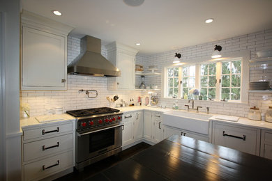 Eat-in kitchen - mid-sized country l-shaped dark wood floor and brown floor eat-in kitchen idea in New York with a farmhouse sink, recessed-panel cabinets, white cabinets, white backsplash, subway tile backsplash, stainless steel appliances, an island and marble countertops