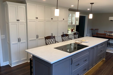 Example of a mid-sized transitional u-shaped dark wood floor and brown floor eat-in kitchen design in Cleveland with an undermount sink, recessed-panel cabinets, white cabinets, gray backsplash, subway tile backsplash, stainless steel appliances, an island and white countertops