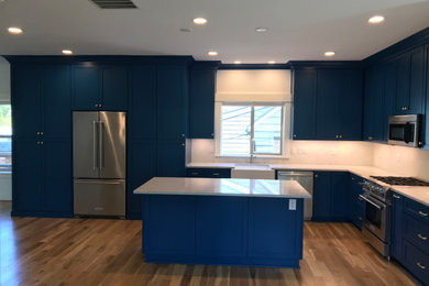 Large trendy l-shaped light wood floor kitchen photo in Portland with an undermount sink, shaker cabinets, blue cabinets, quartzite countertops, white backsplash, ceramic backsplash, stainless steel appliances and white countertops