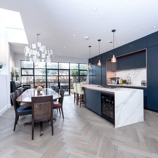 Photo of a medium sized contemporary single-wall kitchen/diner in London with flat-panel cabinets, blue cabinets, marble worktops, white splashback, marble splashback, light hardwood flooring, an island, white worktops and beige floors.