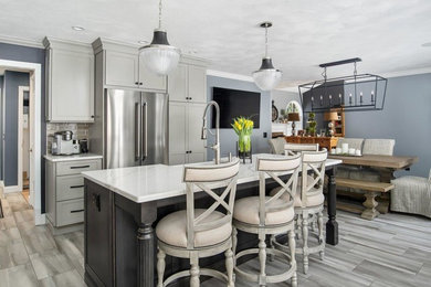Inspiration for a transitional porcelain tile and gray floor eat-in kitchen remodel in Providence with a farmhouse sink, shaker cabinets, stainless steel appliances, an island and white countertops