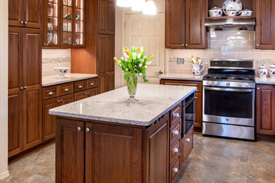 Mid-sized elegant l-shaped vinyl floor and brown floor eat-in kitchen photo in Other with an undermount sink, raised-panel cabinets, quartz countertops, beige backsplash, subway tile backsplash, stainless steel appliances, an island, beige countertops and medium tone wood cabinets