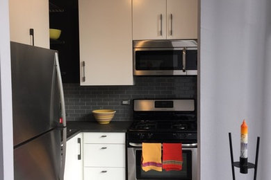 Example of a small trendy l-shaped gray floor eat-in kitchen design in Chicago with flat-panel cabinets, white cabinets, gray backsplash, stainless steel appliances and no island