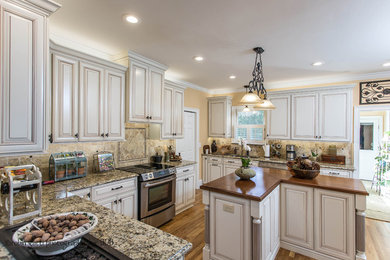 Transitional medium tone wood floor kitchen photo in Atlanta with an undermount sink, raised-panel cabinets, granite countertops, beige backsplash, stainless steel appliances and an island