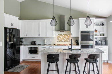 Example of a mid-sized transitional l-shaped laminate floor and brown floor open concept kitchen design in St Louis with an undermount sink, recessed-panel cabinets, white cabinets, quartz countertops, white backsplash, subway tile backsplash, stainless steel appliances, an island and multicolored countertops