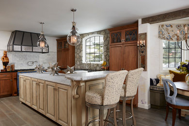 Cette image montre une grande cuisine américaine traditionnelle en bois brun et L avec plan de travail en marbre, îlot, un placard avec porte à panneau encastré, une crédence multicolore et un sol en bois brun.