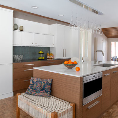 Mid-sized mid-century modern galley medium tone wood floor and brown floor eat-in kitchen photo in Minneapolis with a single-bowl sink, flat-panel cabinets, medium tone wood cabinets, quartz countertops, green backsplash, stainless steel appliances, an island and white countertops