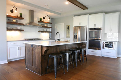 Mid-sized transitional l-shaped medium tone wood floor eat-in kitchen photo in Minneapolis with a single-bowl sink, shaker cabinets, medium tone wood cabinets, quartz countertops, white backsplash, stainless steel appliances, an island and white countertops