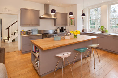 オックスフォードシャーにあるトランジショナルスタイルのおしゃれなキッチン (フラットパネル扉のキャビネット、グレーのキャビネット、木材カウンター、シルバーの調理設備、無垢フローリング、一体型シンク) の写真