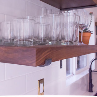 Immagine di una cucina moderna di medie dimensioni con lavello sottopiano, ante in stile shaker, ante nere, top in superficie solida, paraspruzzi bianco, paraspruzzi con piastrelle diamantate, elettrodomestici in acciaio inossidabile e pavimento in gres porcellanato
