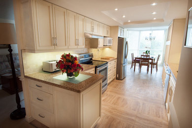 Mid-sized transitional u-shaped vinyl floor enclosed kitchen photo in Toronto with recessed-panel cabinets, white cabinets, granite countertops, beige backsplash, ceramic backsplash, stainless steel appliances, a double-bowl sink and no island