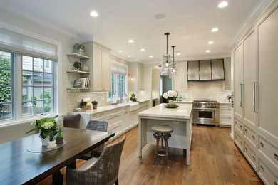 Example of a large transitional u-shaped medium tone wood floor and brown floor eat-in kitchen design in Chicago with a farmhouse sink, recessed-panel cabinets, white cabinets, quartzite countertops, white appliances, an island and white countertops
