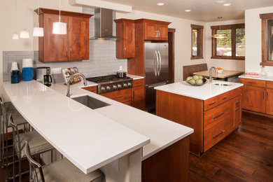 Example of a mid-sized trendy u-shaped dark wood floor and brown floor eat-in kitchen design in Denver with an undermount sink, recessed-panel cabinets, dark wood cabinets, quartz countertops, gray backsplash, porcelain backsplash, stainless steel appliances, an island and white countertops